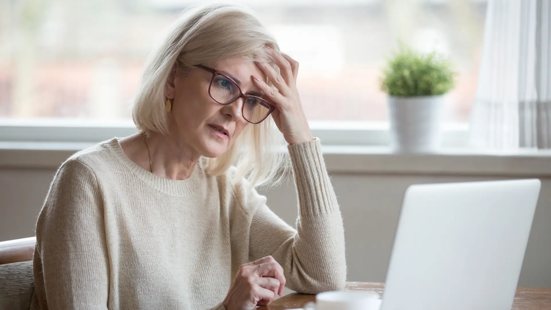 what-causes-brain-fog Woman experiencing difficulty concentrating and symptoms associated with brain fog while working at a computer.